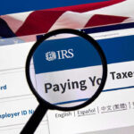 Tax Tsunami Looms—Retirees Left Exposed Magnifying glass over IRS website for paying taxes