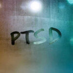 Outrage Erupts Over Unseen Trauma Epidemic PTSD written on a foggy glass surface
