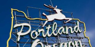 Neon sign reading Portland Oregon with a leaping deer against a blue sky