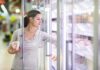 A woman shopping in the frozen food aisle of a supermarket