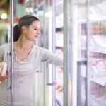 Frozen Food Frenzy—Grocery Bills Slashed Overnight A woman shopping in the frozen food aisle of a supermarket