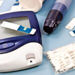 Diabetes Icon EXPOSED — Doctors Stunned by Brain Link Blood glucose monitor with testing strips and a lancing device on a blue background