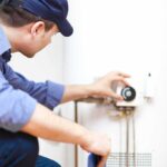 Renovation NIGHTMARE—Homeowners Stunned By One Missed Step Plumber adjusting the settings on a water heater