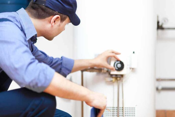 shutterstock_142322101.jpg Plumber adjusting the settings on a water heater