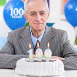 Elderly man celebrating his 100th birthday with a cake and candles