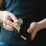 Fall Money Trap—Most Americans Walk Right In Person holding a wallet with cash inside