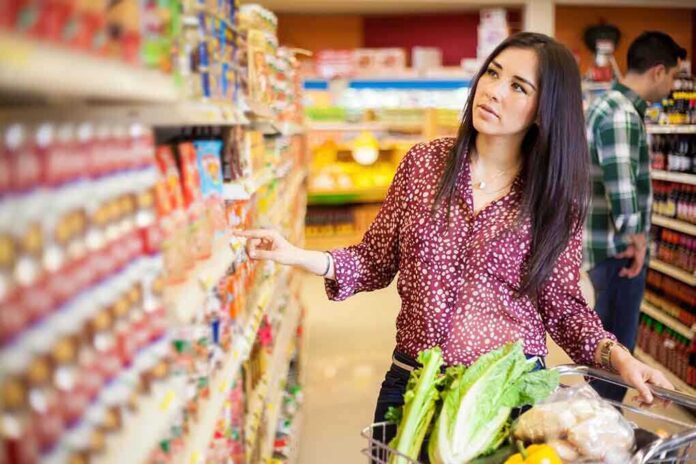 shutterstock_182011403.jpg Woman shopping in a grocery store aisle with a cart full of vegetables