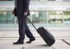 A businessman in a suit walking with a suitcase at an airport