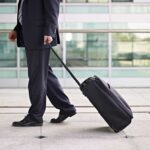Business Travel EXPOSED: The Hidden Exhaustion Trap A businessman in a suit walking with a suitcase at an airport