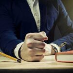 Virtual Help Wanted: Why Everyone’s Hiring Assistants A man's clenched fist resting on a desk with office supplies nearby