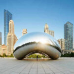 Cloud Gate sculpture with skyline of skyscrapers behind it