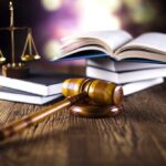 A gavel, legal books, and scales of justice on a wooden table