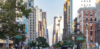 Busy city street with cars and people crossing