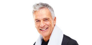 Smiling older man wearing a black shirt with a towel around his neck