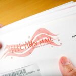 Voting Could Change Forever For These 17 States A hand holding an envelope labeled Official Election Mail