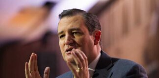 A man in a suit passionately speaking with expressive hand gestures