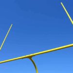 Yellow football goalpost against a clear blue sky