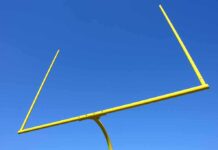 Shocking ACCUSATIONS — Coach Turned FUGITIVE Yellow football goalpost against a clear blue sky