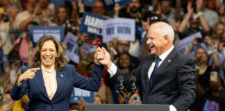 Two people holding hands at a campaign rally.