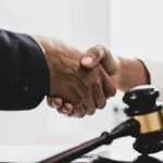 Handshaking near a gavel on desk.