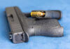 Handgun on blue fabric with visible bullet cartridge.