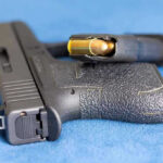Shocking New Video Twists Alex Pretti Case Handgun on blue fabric with visible bullet cartridge.