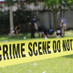 Teen Discovers Tragic Crime Scene at Home Yellow crime scene tape blocking grassy area.