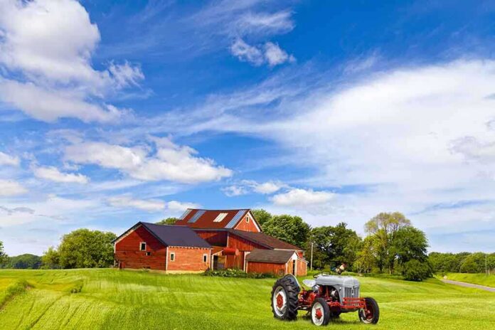 shutterstock_135351362.jpg A vintage tractor in front of a red barn on a sunny day