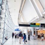 Interior of an airport terminal with travelers and signage