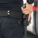 Person holding a gun in a holster.