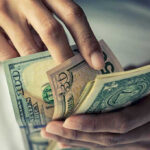 Person holding multiple U.S. dollar bills.