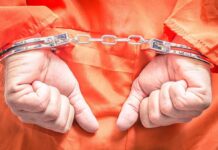 Hands in handcuffs wearing an orange jumpsuit