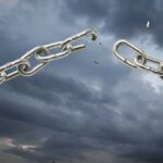 A broken metal chain against a stormy sky