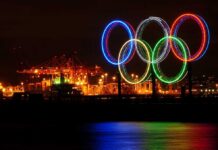Illuminated Olympic rings displayed at night over a harbor
