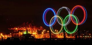 Illuminated Olympic rings displayed at night over a harbor