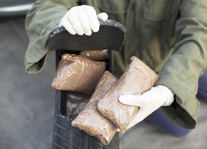 160035851 Person handling packages wearing gloves and green jacket.