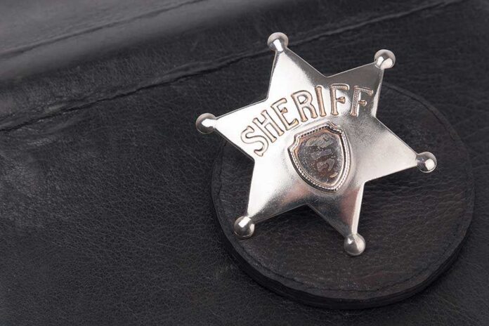 A silver sheriff badge resting on a black leather surface
