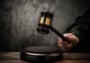 A judges gavel poised to strike a sound block