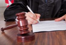 A judge signing a legal document with a gavel in the foreground