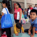 Massive $250M Fraud: 41-Year Sentence Stuns! People waiting outside carrying bags, boys sitting and playing.