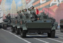 Tanks with military personnel in street parade formation.