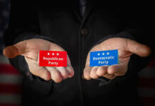 Hands holding Republican and Democratic Party cards.