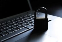 Slack’s AI Peeks Into Employee Gripes A padlock resting on a laptop keyboard in a dimly lit environment