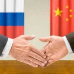 Zelensky Accuses Kremlin of Ceasefire Trickery Two hands shaking in front of Russian and Chinese flags