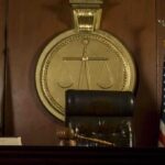 Judge Apologizes In Trump Assassin Case A judges bench in a courtroom with a gavel and flags