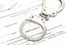 Councilman in Cuffs—The Vetting Failure Handcuffs on top of an arrest warrant document.