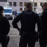 World Cup Chaos: Highway Gunman Vanishes Three police officers standing on a city street.