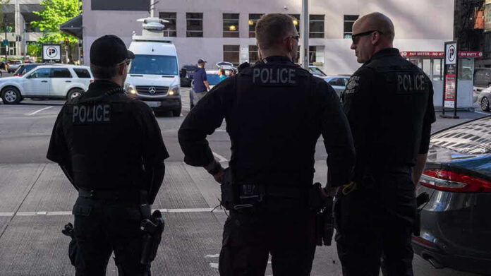 1386794081-1 Three police officers standing on a city street.