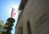 Citizenship Crackdown Explodes — Who’s Next? American flag at Department of Justice building exterior.