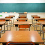 Empty classroom with desks and a chalkboard.
